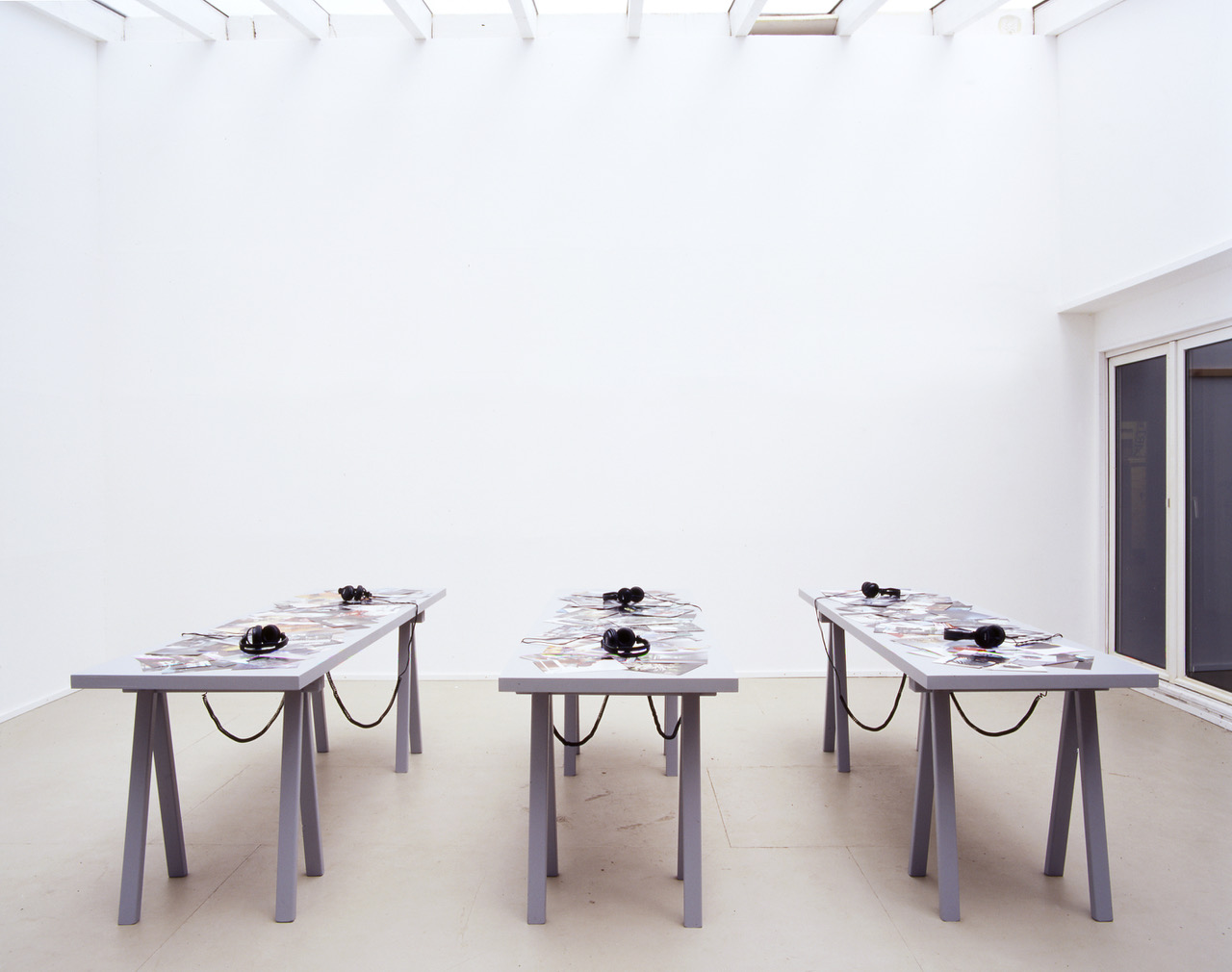 Photograph of the three tables with sets of headphones on them at the PLOTS installation.